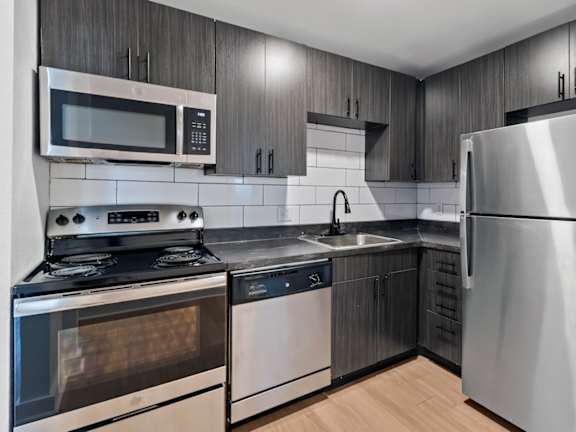 The Canvas modern kitchen with brown cabinets and stainless steel appliances