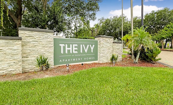 A sign that says "The Ivy Apartment Homes" in front of a stone wall.