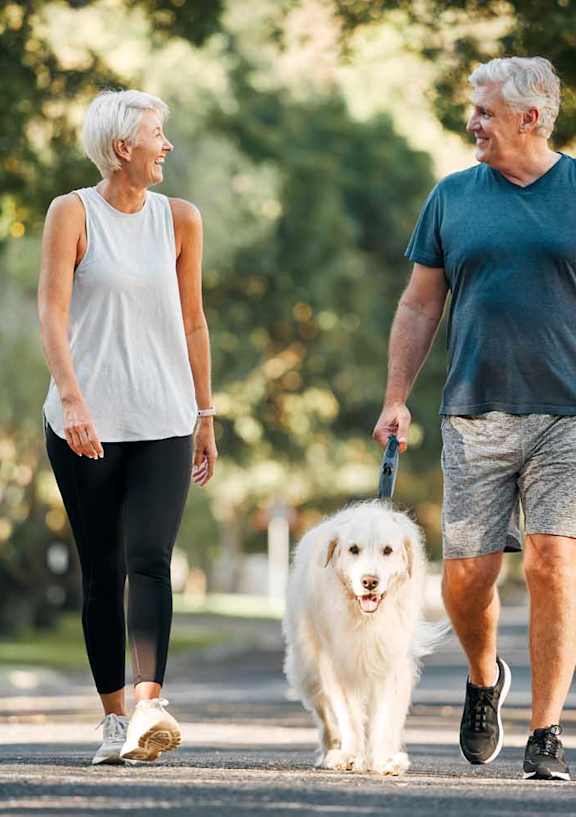an older couple walking their dog in the park