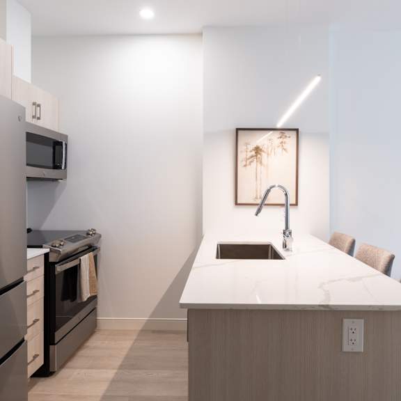 A modern kitchen with a refrigerator, oven, and sink.
