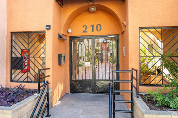 The entrance to a building with a black gate and a number 210 above it.