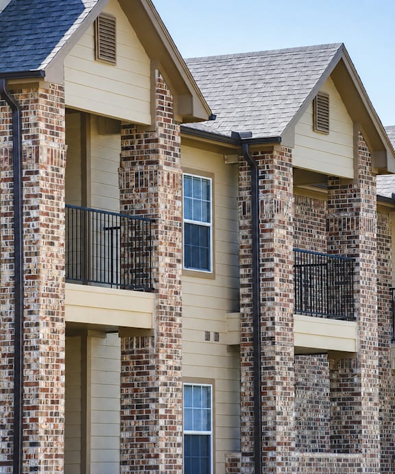 A row of houses with balconies and brick pillars.