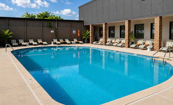 A large swimming pool with lounge chairs and a building in the background.