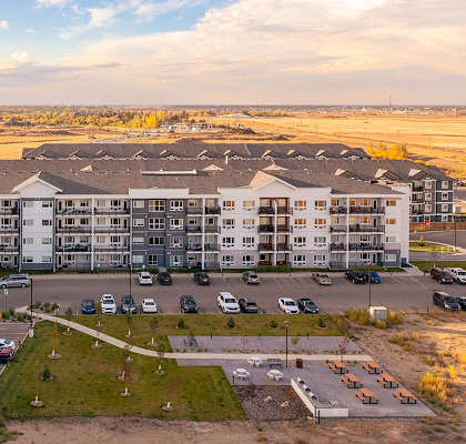 an aerial view of an apartment building with cars parked in a parking lot