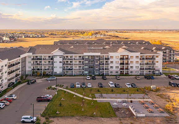 an aerial view of an apartment building with cars parked in a parking lot