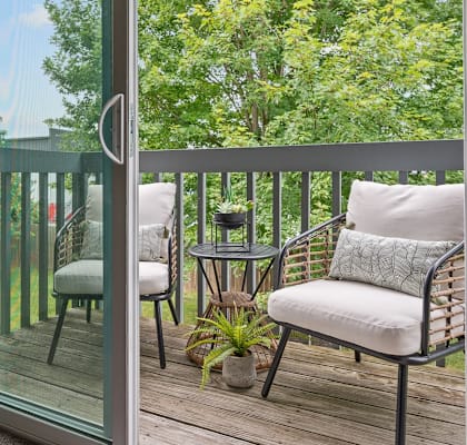 a balcony with two chairs and a table and a sliding glass door