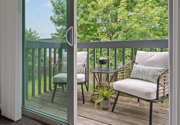 a balcony with two chairs and a table and a sliding glass door