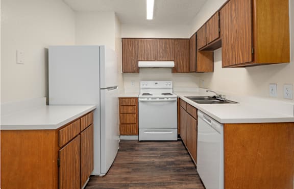 A kitchen with white appliances and wooden cabinets.