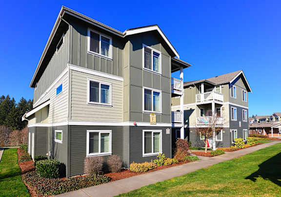 A row of modern townhouses with balconies and landscaped front yards.
