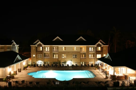 a large swimming pool in front of a building at night