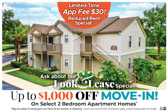 A large two-story apartment building with a red and white advertisement offering a limited-time app fee discount and a move-in special.