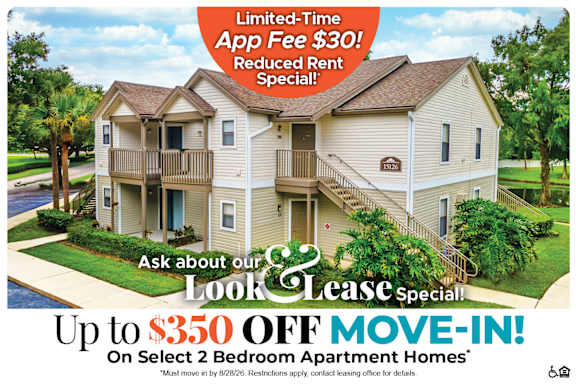 A large two-story apartment building with a red and white advertisement offering a limited-time app fee discount and a move-in special.