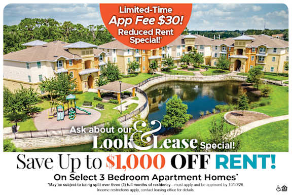an aerial view of a park with a pond and apartments