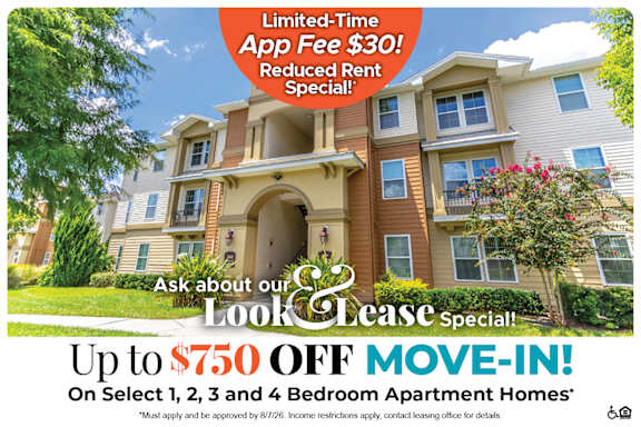 A large, multi-story apartment building with a sign offering a limited-time app fee reduction and a move-in special.