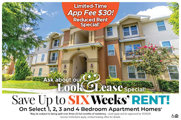 A large, multi-story apartment building with a sign offering a limited-time app fee discount and reduced rent special.