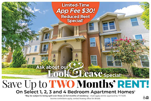 A large, multi-story apartment building with a sign offering a limited-time app fee discount and reduced rent special.