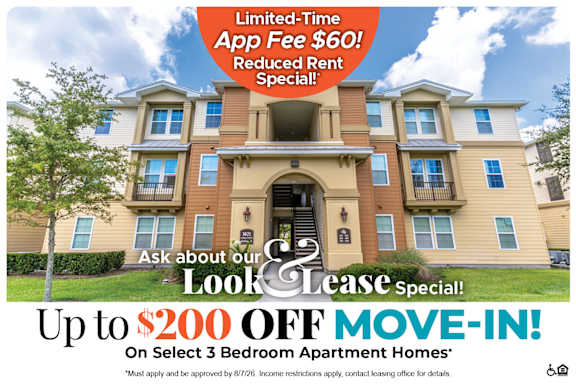 A large, multi-story apartment building with a sign offering a limited-time app fee discount and reduced rent special.