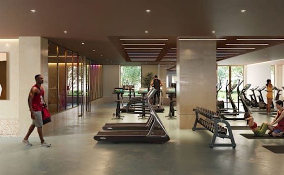 A man is walking in a gym with treadmills and other exercise equipment.