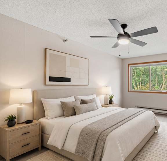 A bedroom with a large bed, a ceiling fan, and a window with a view of trees.