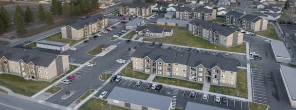 A large apartment complex with a parking lot in front.