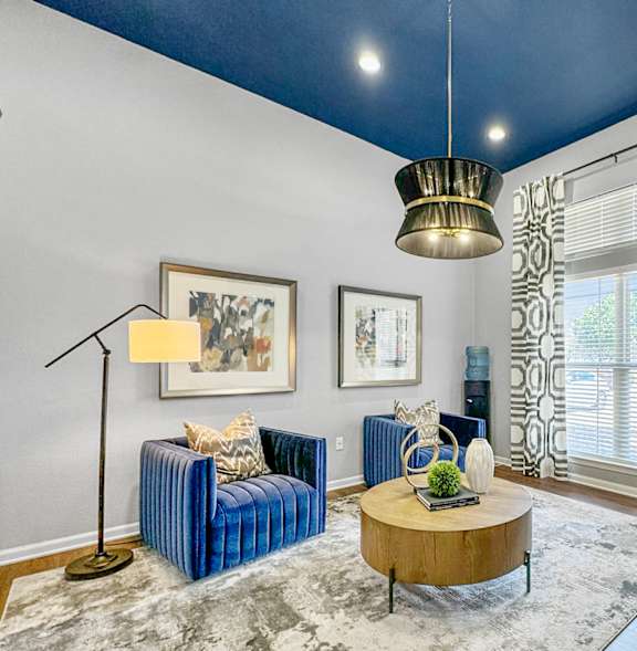 A living room with a blue couch, a coffee table, and a lamp.at 92West, West Des Moines, IA