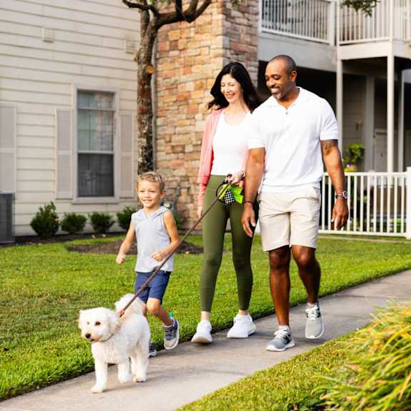 Family walking dog on sidewalk