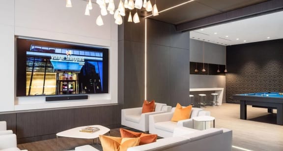 a living room with a large screen tv and a pool table