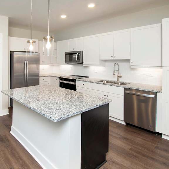 A kitchen with white cabinets and a granite countertop.