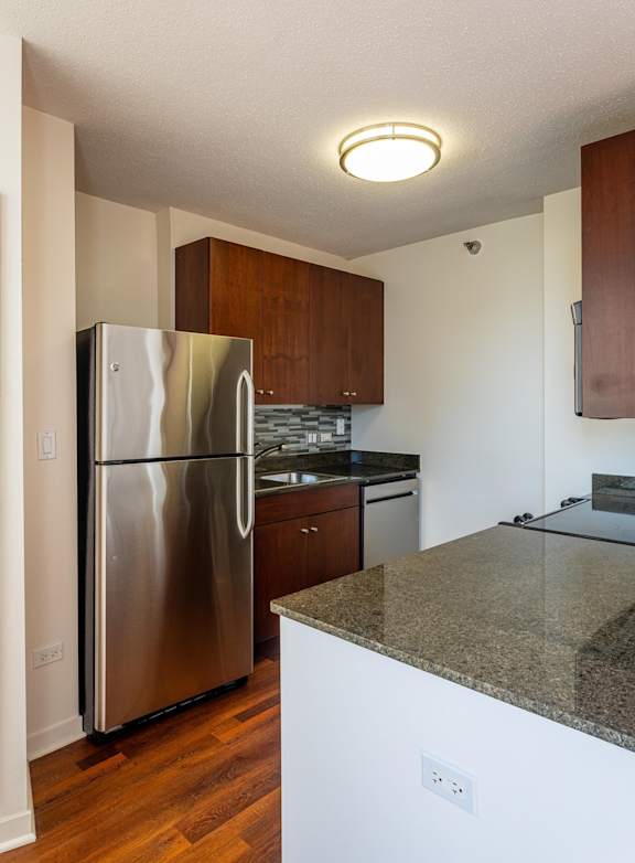 A kitchen with a stainless steel refrigerator and granite countertops.