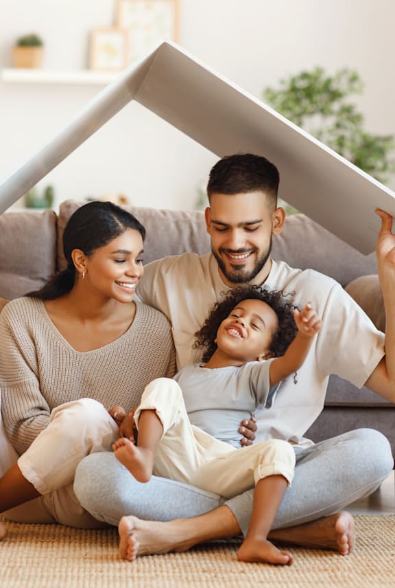 A family of three is sitting on the floor with a large white object between them. at Grand Manor Apartments , Grand Junction