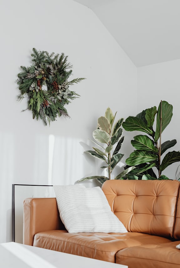 A brown leather couch with a white pillow and a wreath on the wall. at Willow Grove Apartments , Clifton