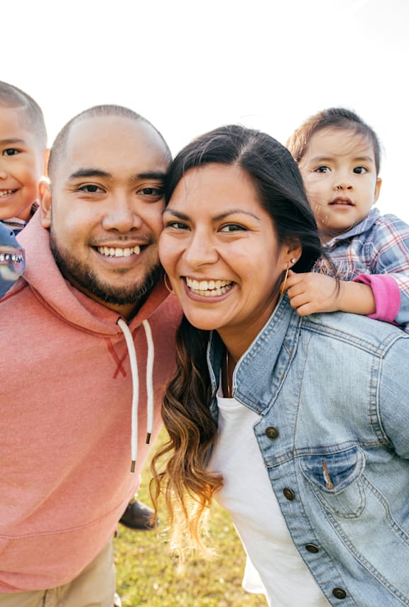 A family of four is smiling and enjoying a sunny day outdoors.