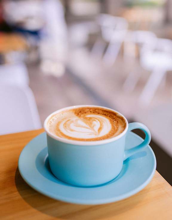 A cup of coffee with milk on a saucer on a wooden table.