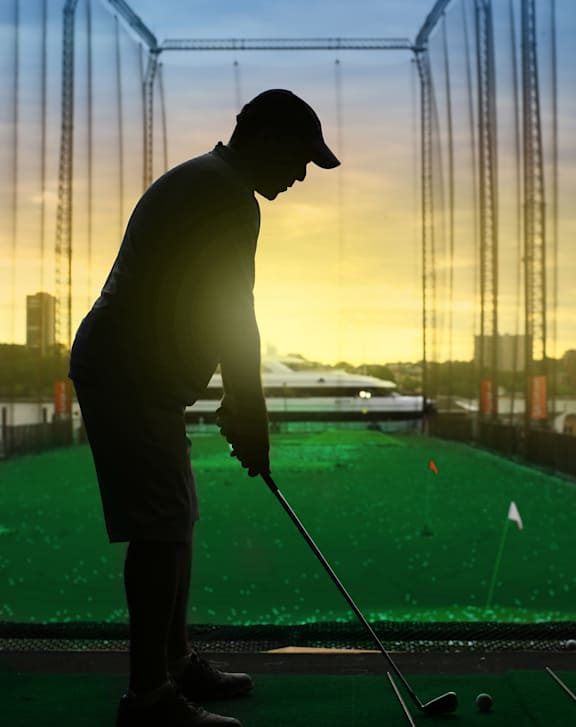 A man is playing golf on a green mat.