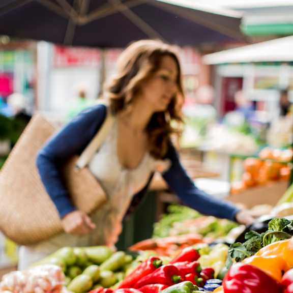 A woman is shopping for vegetables at a market.