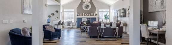 A spacious living room with a dark blue sofa and a wooden floor.