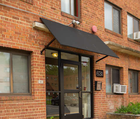 the front door of a brick building with a black awning
