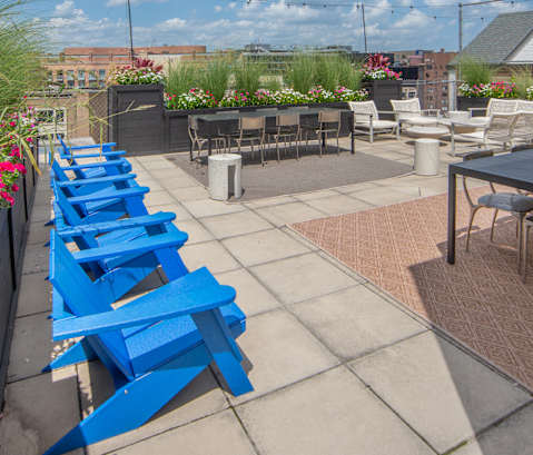 a row of blue tables and chairs on a rooftop patio