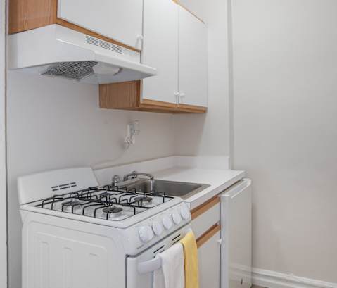 a small kitchen with white appliances and white cabinets and a white stove