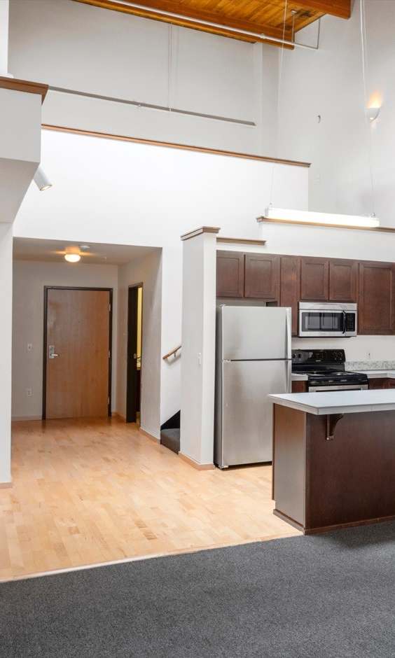 A kitchen with a refrigerator, sink, and cabinets.