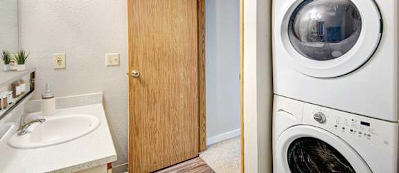 A white washing machine sits in a laundry room next to a sink.