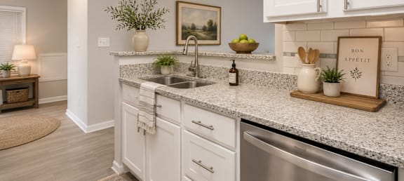 A kitchen with white cabinets and a marble countertop.