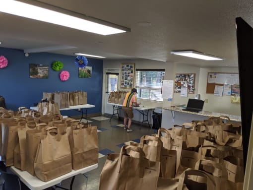 Mutual Housing staff organize bags of food on folding tables in the River Garden community room