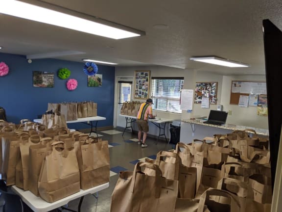 Mutual Housing staff organize bags of food on folding tables in the River Garden community room