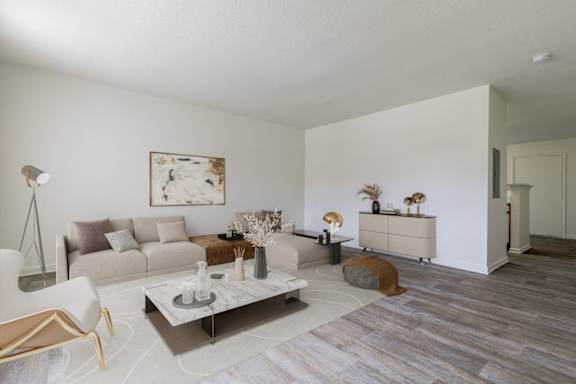 A modern living room with a white sofa, a coffee table, and a painting on the wall.