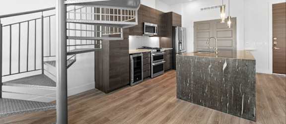 A modern kitchen with a wooden floor and a staircase.