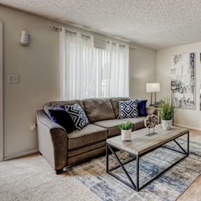 A living room with a couch, a chair, a coffee table, and pictures on the wall.