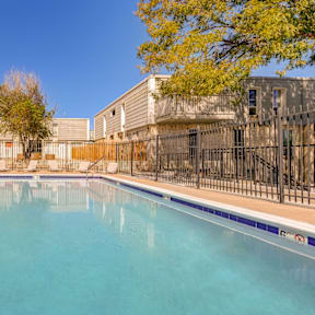 A swimming pool in a sunny day surrounded by a fence.