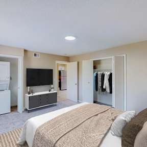 A bedroom with a bed, a television, and a refrigerator.