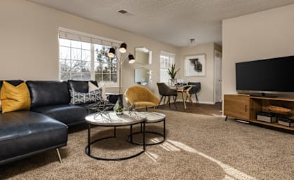 A living room with a black leather couch and a coffee table.
